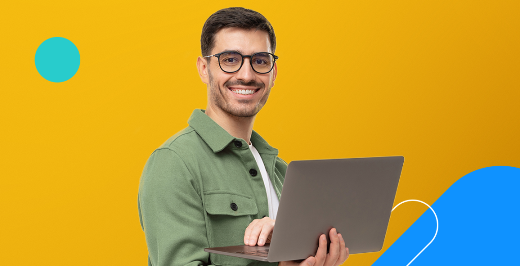 Homem segurando computador em frente a fundo amarelo