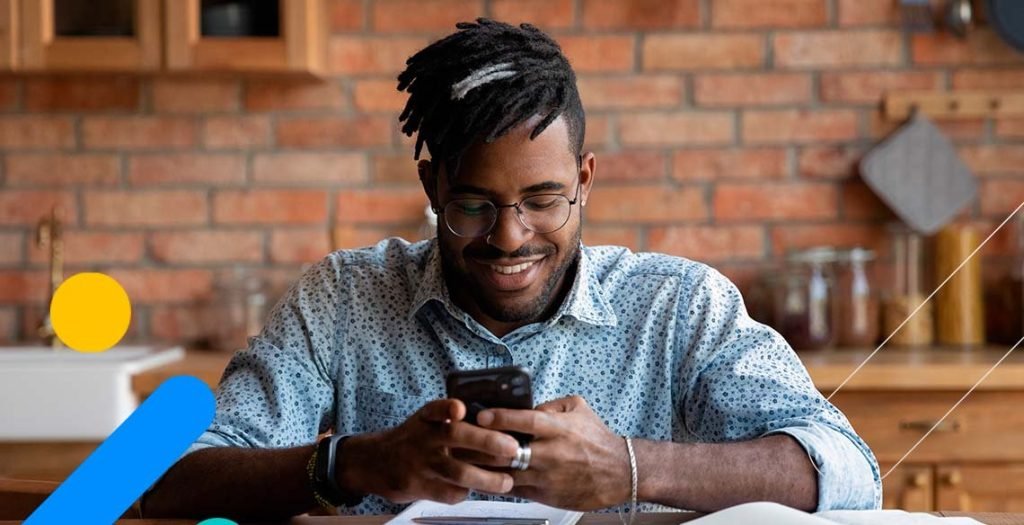 Homem sorrindo mexendo no celular