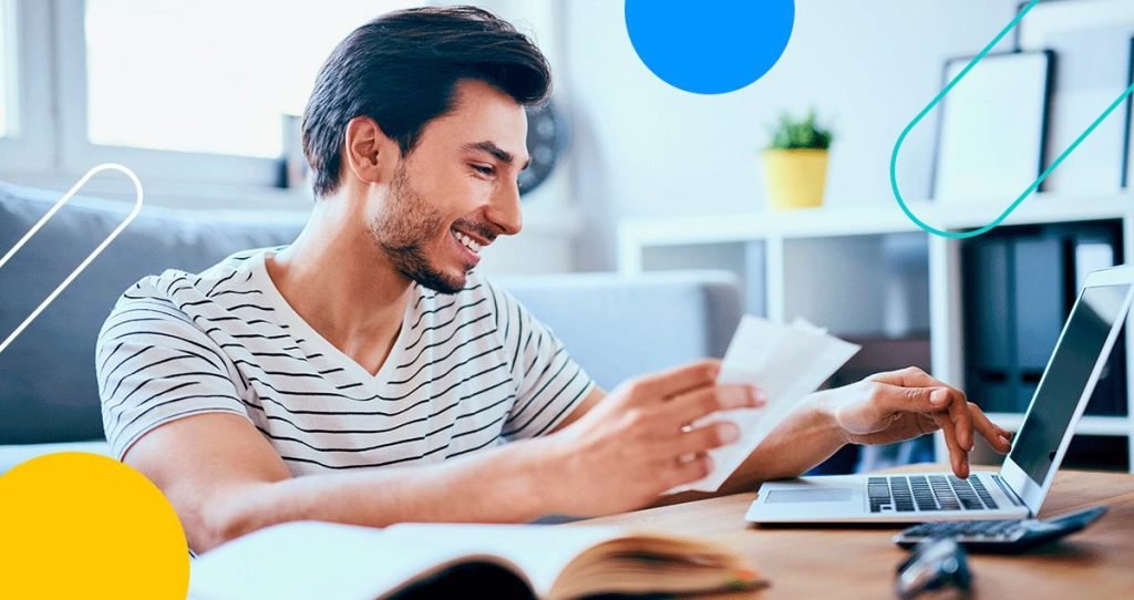 Homem segurando papel em frente a computador