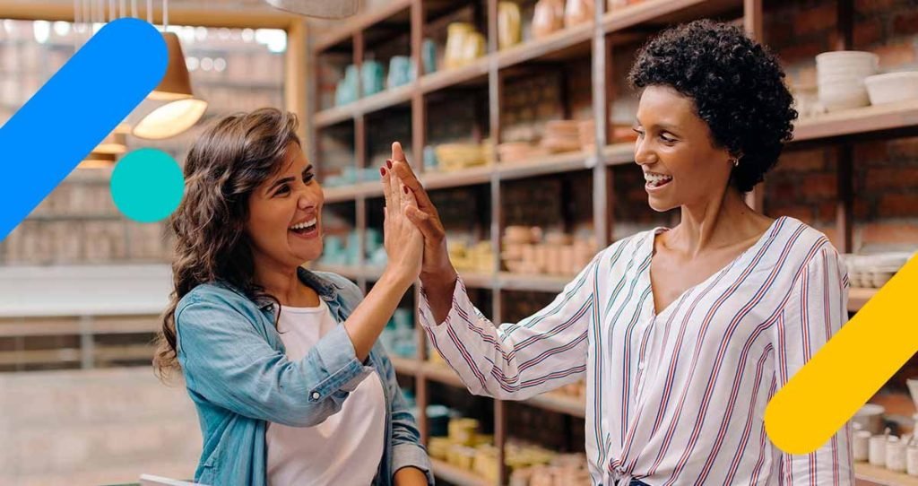 Duas mulheres sorrindo e batendo as palmas das mãos