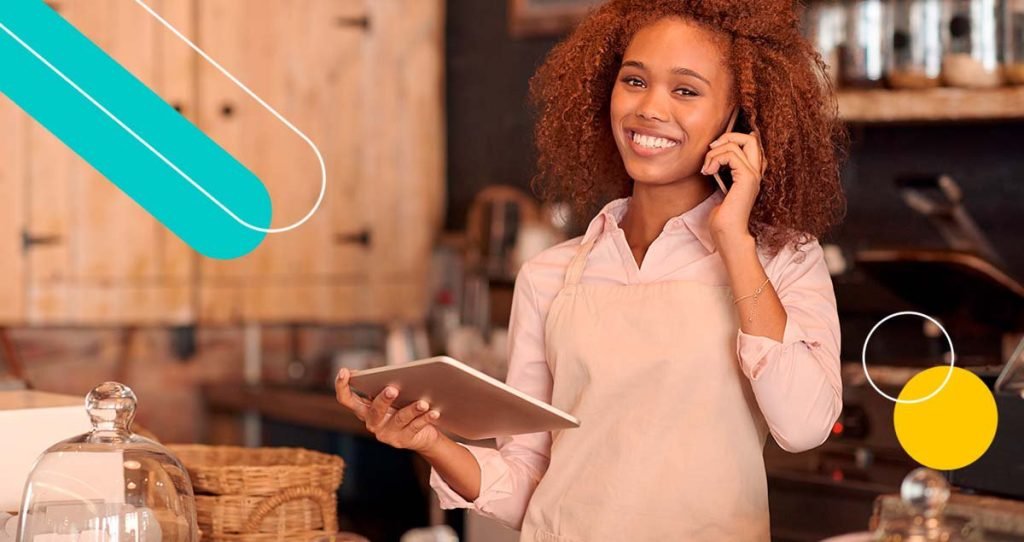 Mulher sorrindo falando no telefone com tablet na mão